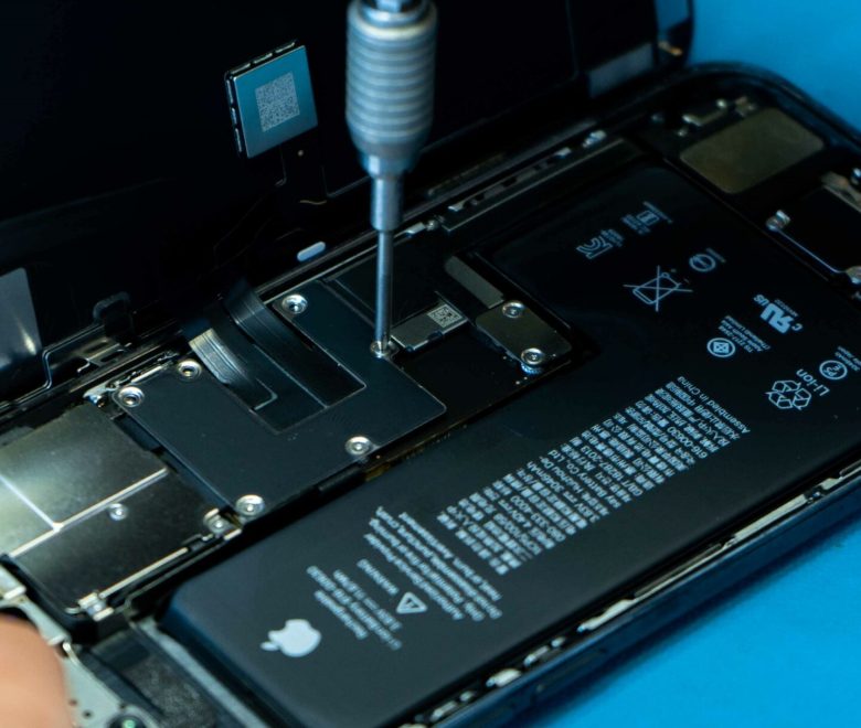 Un smartphone à réparer avec sa façade avant ouverte. D'autres pièces doivent être retirées pour pouvoir remplacer la batterie défectueuse.